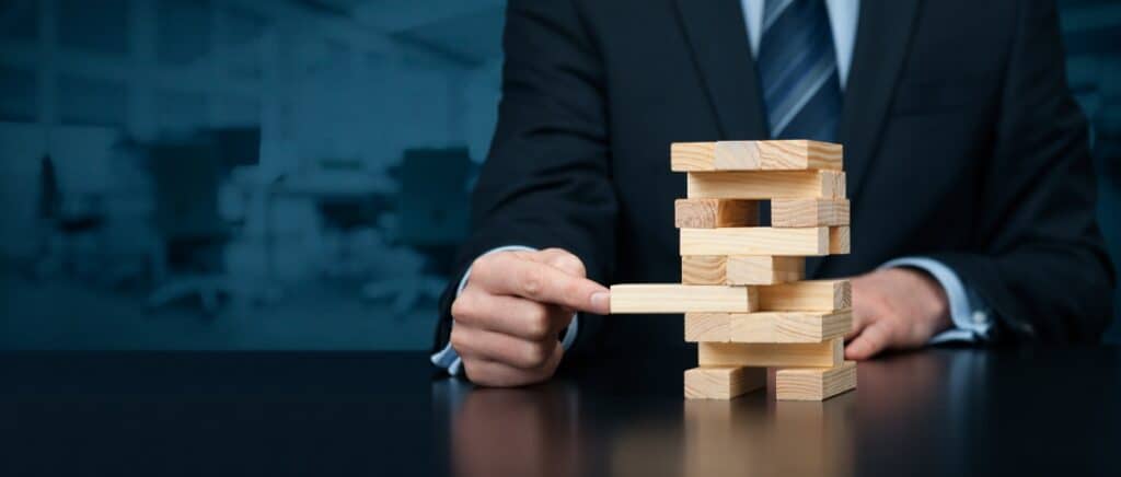 business person removing wood tower representing actuarial valuation risks