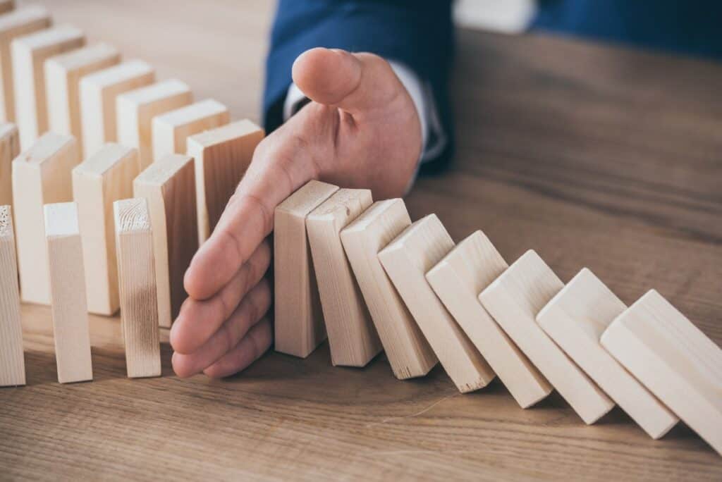 Graphic depicting risk management in actuarial science, showing a risk manager blocking a domino effect