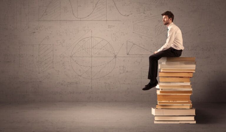 actuarial student sitting on books - Actuarial Exam Study Techniques